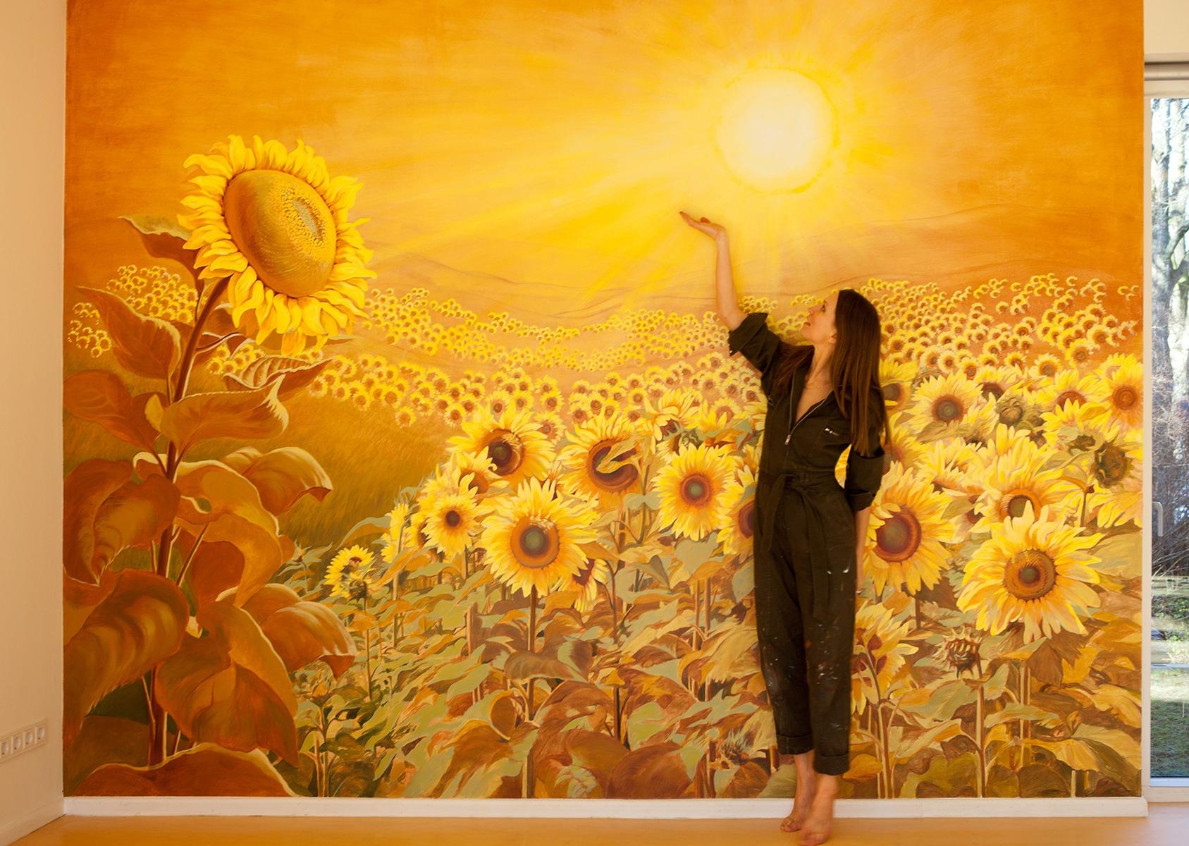 Die Künstlerin Elena Wuest vor Ihrem Wandbild Lichtemanation - Wandmalerei mit Sonnenblumen